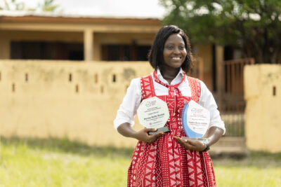 Portia in red dress standing outside her school holding her trophies