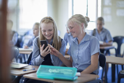 Students in classroom looking at a phone